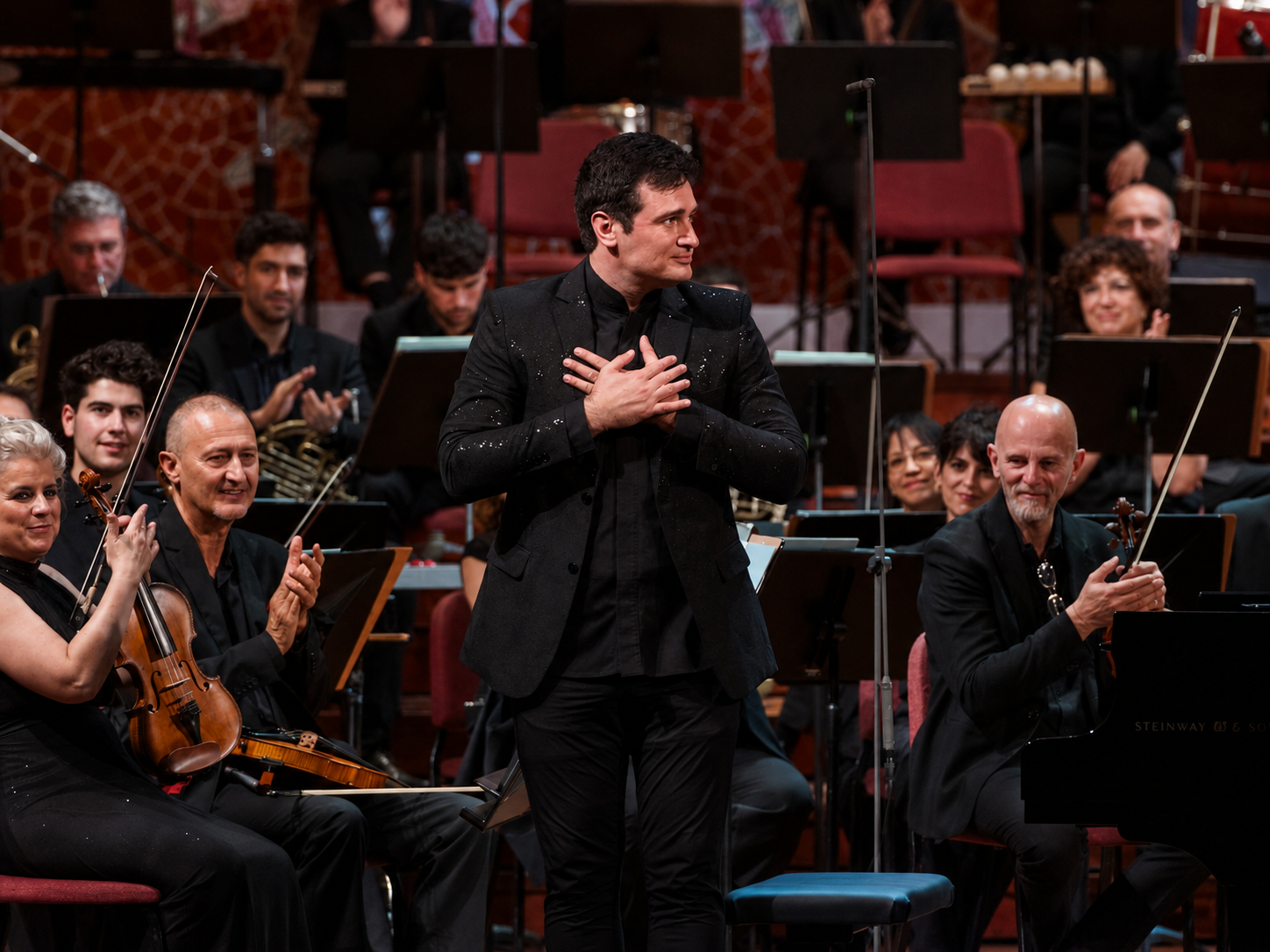 Artem Kuznetsov standing with his hands over his heart before the orchestra at Palau de la Música Catalana